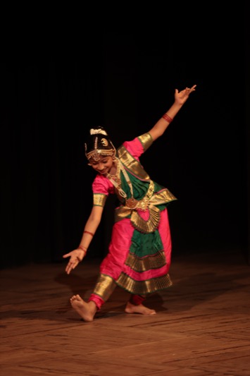 A child performing a classical dance on stage