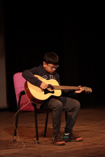 A child mid-performance under stage lights